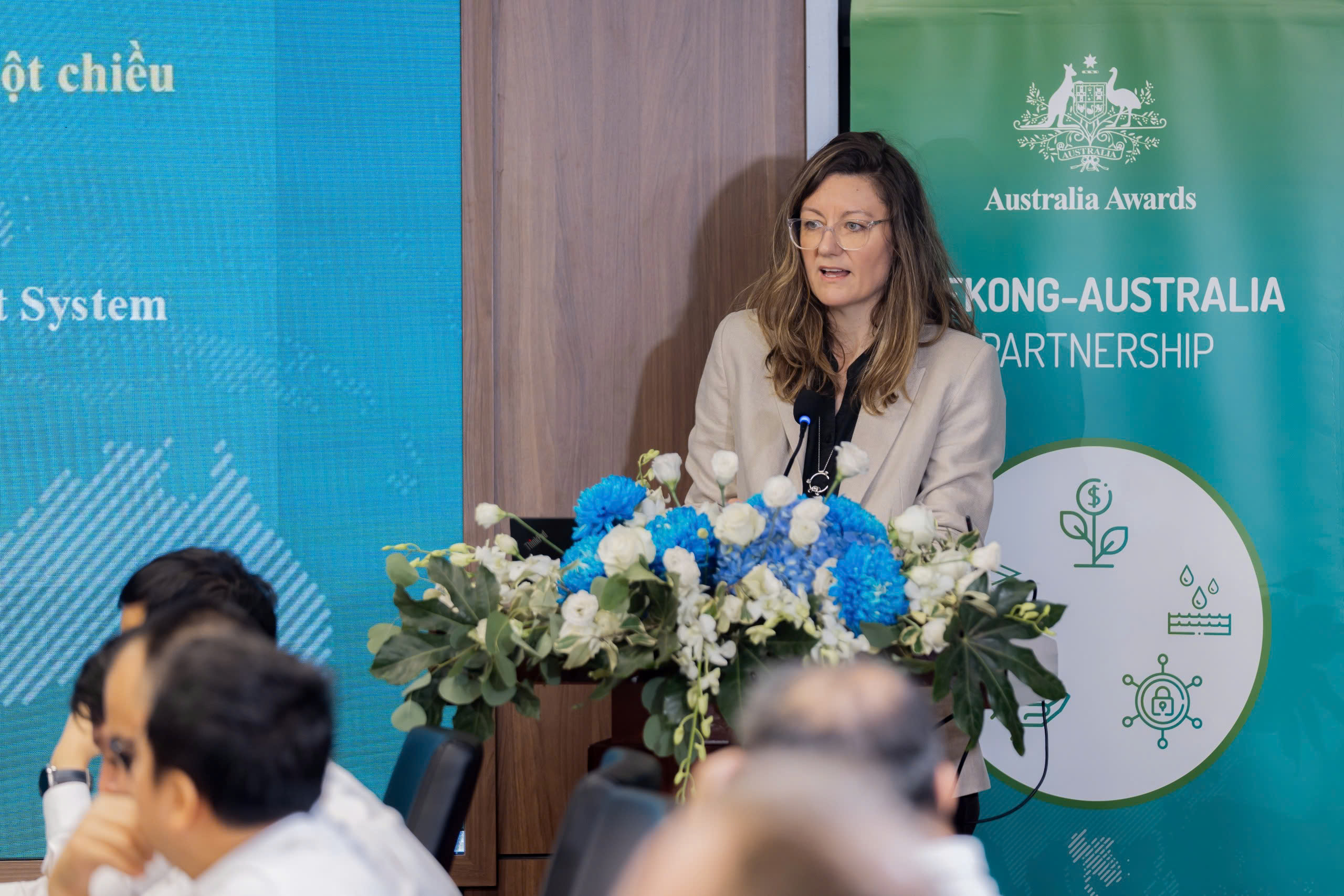 A person standing at a podium with flowersDescription automatically generated